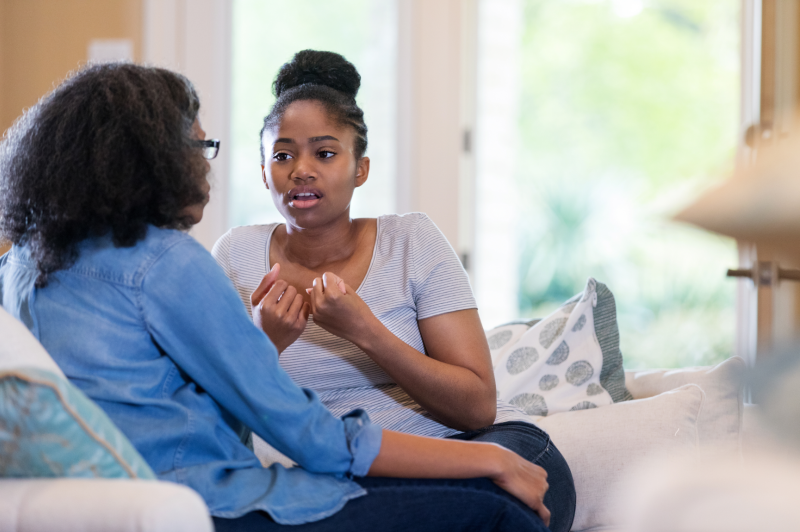 A parent and adult child in a deep conversation in the living room. This could represent speaking honestly and being yourself with an online therapist in Ontario to find life fulfillment. They can help you create a fulfilling life in Ontario, CA, and other more.
